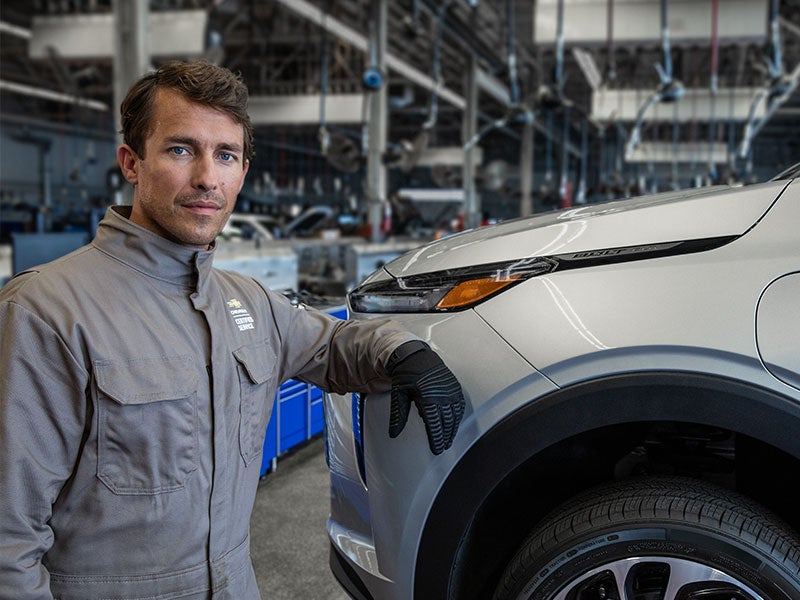 A technician standing in front of a silver vehicle.