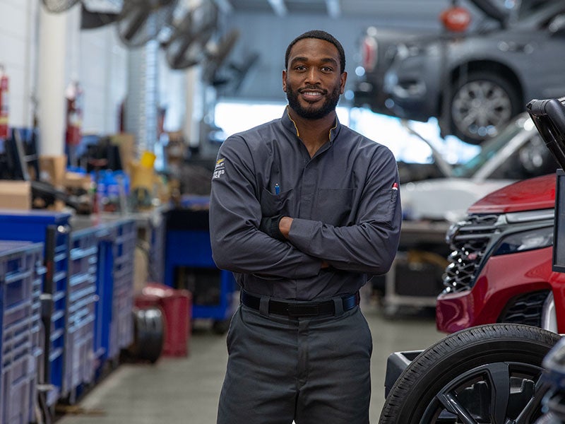 A technician removing the drain plug from under a vehicle.