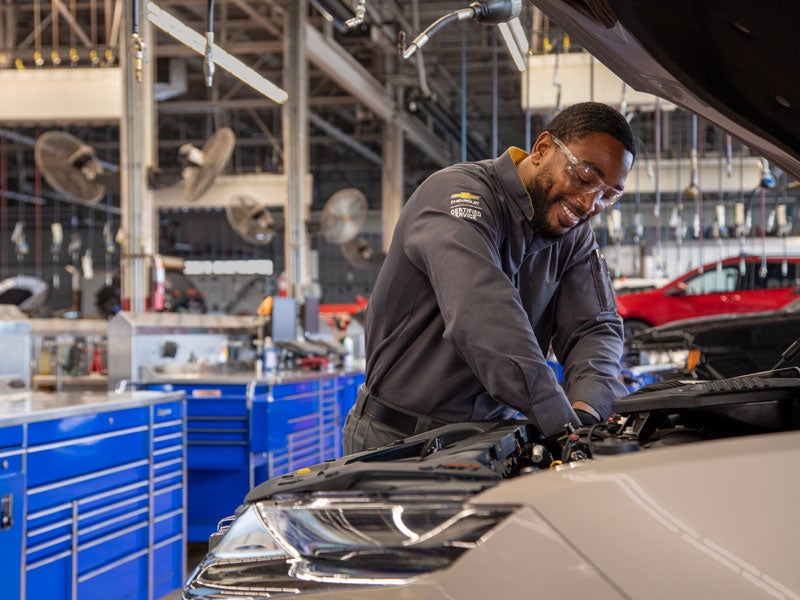 A technician standing in front of a silver vehicle.