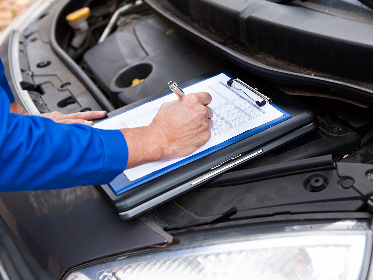 A technician removing the drain plug from under a vehicle.