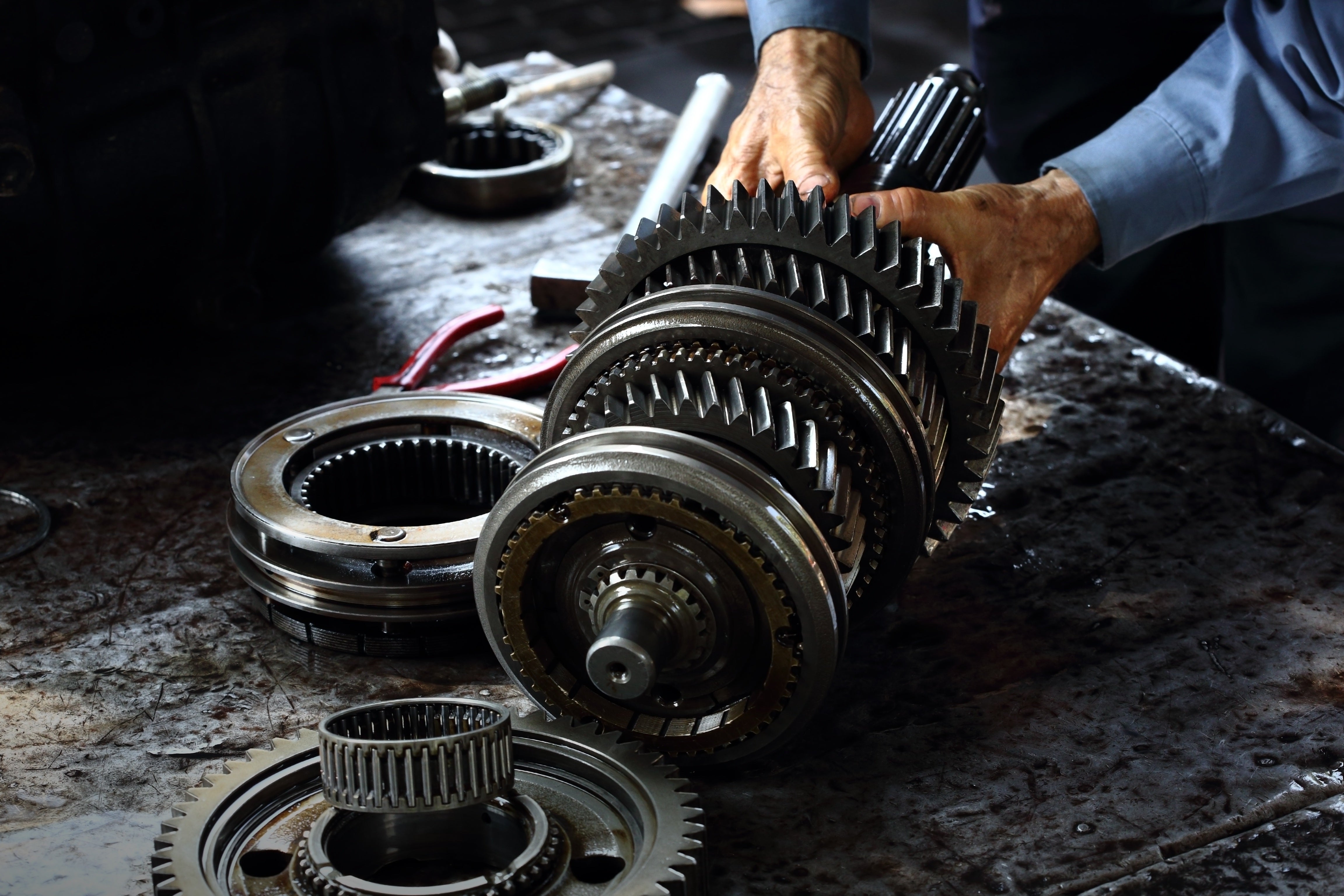 A technician removing the drain plug from under a vehicle.